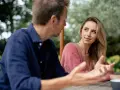 Un homme parle à une femme, son regard captivé par elle. Elle semble écouter attentivement, son expression suggérant le **hero instinct**.