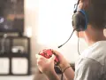 Un jeune homme, casque sur les oreilles, manette rouge en main, plongé dans ses jeux vidéos. Il semble que mon mec préfère ses jeux vidéos à moi.