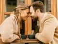 Un couple partage un moment intime, leurs fronts se touchant, illustrant l'effet miroir en amour. Deux tasses de café attendent sur la table.