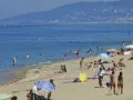 Plage bondée, baigneurs dans l'eau bleue. Combien de temps avant d'aller chez lui ? La journée s'étire.