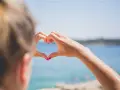 Message après premier rendez-vous avec un homme : un cœur formé par des mains mouillées sur fond de mer bleue.