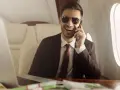 Un homme d'affaires souriant, lunettes de soleil, au téléphone dans un jet privé. Il semble rencontrer un homme riche pour conclure un accord.