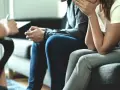 Un couple en pleine thérapie de couples, assis sur un canapé, échangeant avec un thérapeute.