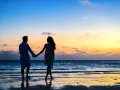 Silhouettes d'un couple se tenant la main sur une plage au coucher du soleil. Il tient à moi mais n'est pas amoureux, juste un ami.
