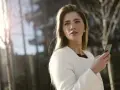 Une femme en manteau blanc tient un téléphone, prête à challenger un homme par sms.