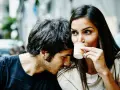 Un homme murmure à l'oreille d'une femme qui boit son café. Un tendre début de relation, peut-être le surnom qu'il vient de lui donner.