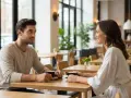 Un homme séducteur et une femme souriante partagent un café. Les signes de complicité sont évidents dans leur regard.