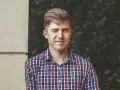 Un homme en chemise à carreaux fait un clin d'œil à une femme, un sourire malicieux aux lèvres.