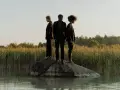 Trois personnes en noir, sur un rocher au milieu de l'eau, symbolisant la non monogamie éthique et la liberté de choix.