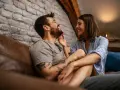 Un couple rit et se regarde tendrement sur un canapé. Le vrai amour, c'est cette complicité.