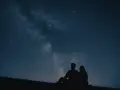 Un couple en silhouette admire la Voie lactée. Une idée de rendez-vous romantique parfait sous les étoiles.