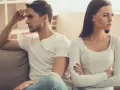 Un couple assis sur un canapé, dos à dos, visiblement en conflit. Elle croise les bras, l'air contrarié, comme s'il la prenait pour acquise.