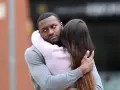 Un homme étreint une femme, mais son regard trahit des signes qu'il parle à une autre.