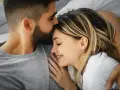Un homme embrasse le front d'une femme endormie, un moment de tendresse calin amoureux.