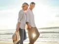Un couple profite d'un rendez-vous amoureux sur la plage, main dans la main, au coucher du soleil.