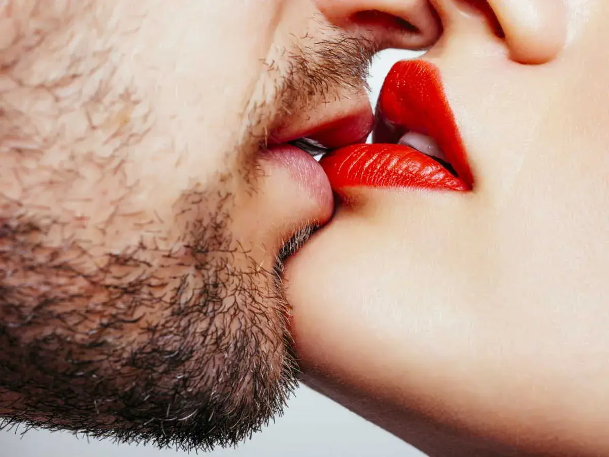 Un homme barbu et une femme aux lèvres rouges apprennent comment embrasser.