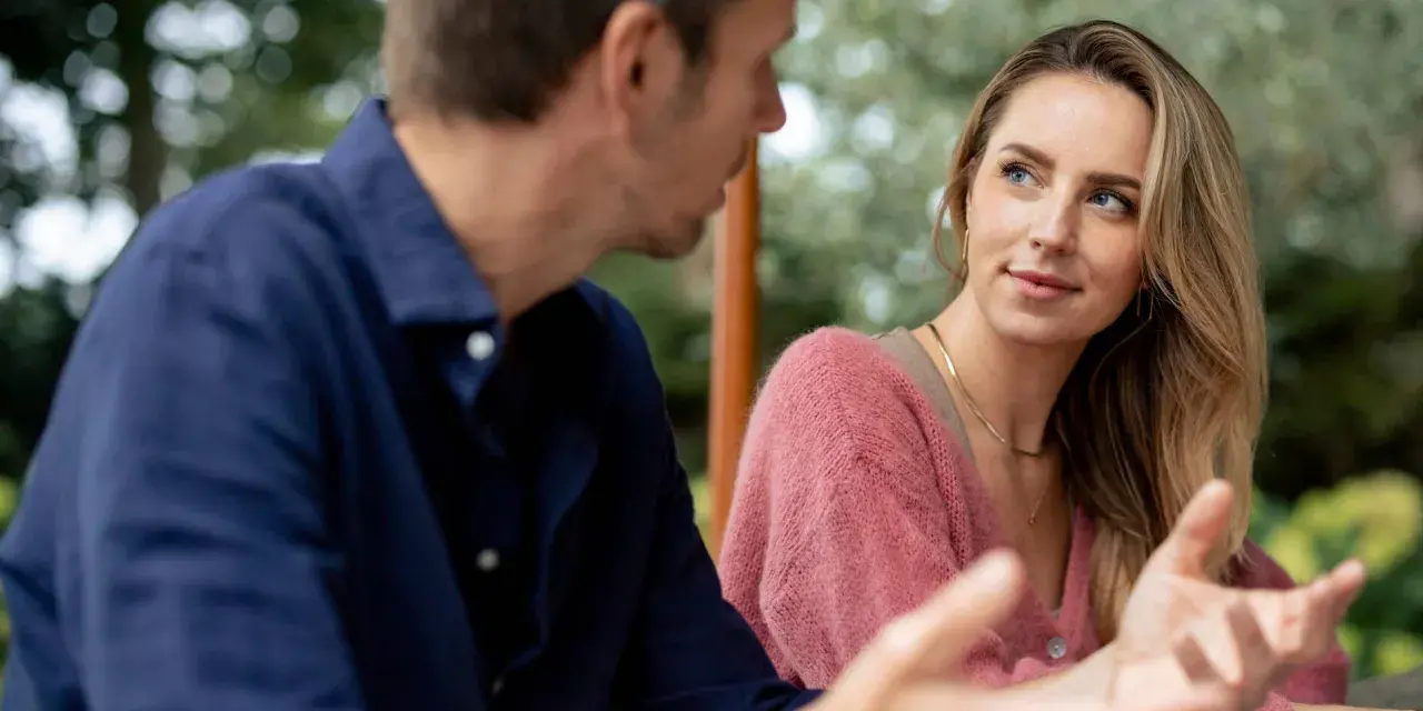 Un homme parle à une femme, son regard captivé par elle. Elle semble écouter attentivement, son expression suggérant le **hero instinct**.