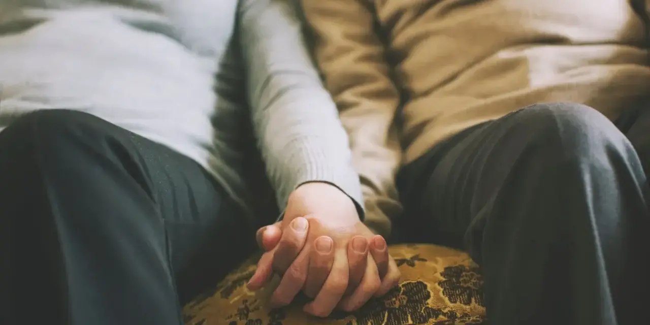 Mains jointes d'un couple qui ne se voit que le week-end, un moment précieux de connexion et de réconfort partagé.