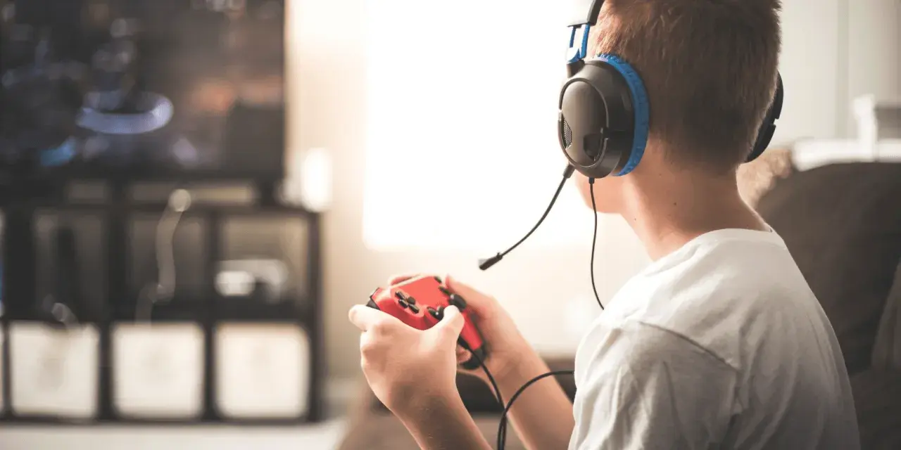 Un jeune homme, casque sur les oreilles, manette rouge en main, plongé dans ses jeux vidéos. Il semble que mon mec préfère ses jeux vidéos à moi.