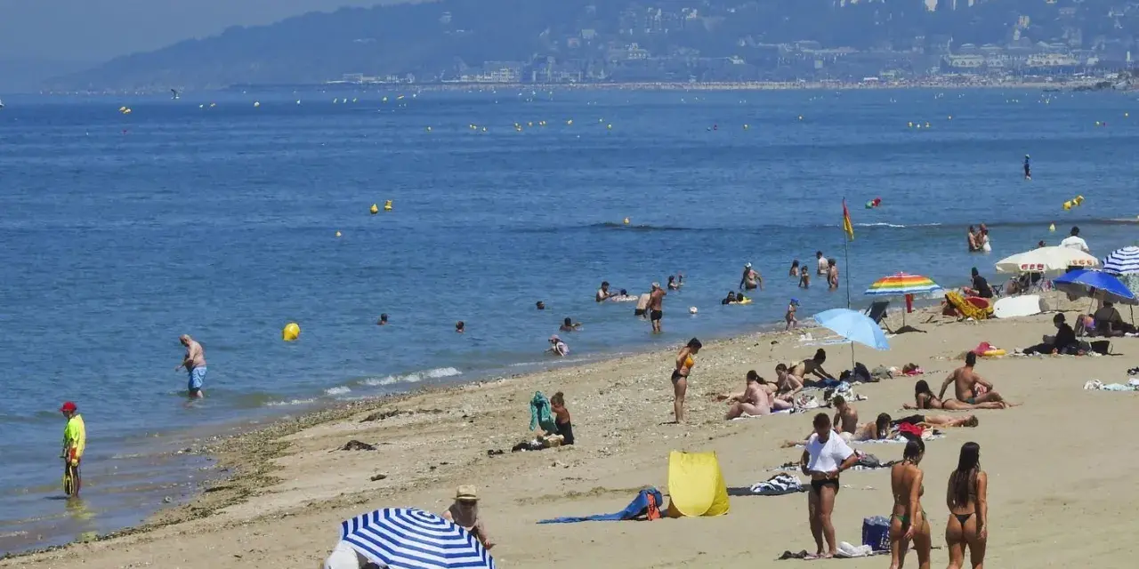 Plage bondée, baigneurs dans l'eau bleue. Combien de temps avant d'aller chez lui ? La journée s'étire.