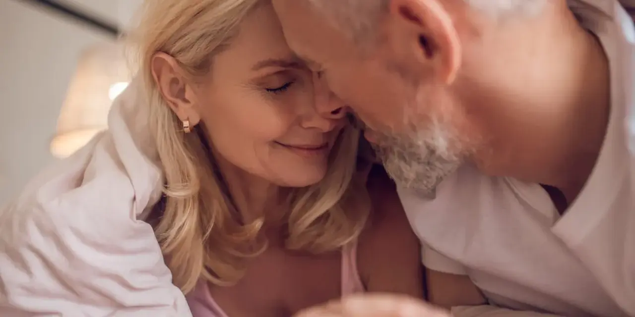 Couple âgé sous une couverture, évoquant la tendresse malgré la baisse de libido chez l'homme de 50 ans.