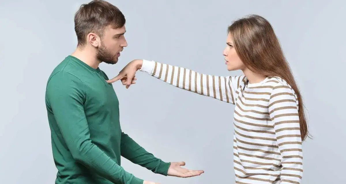 Une femme pointe du doigt un homme, exprimant son mécontentement. Ce geste symbolise les choses à ne pas accepter en couple, comme le manque de respect ou la communication agressive.