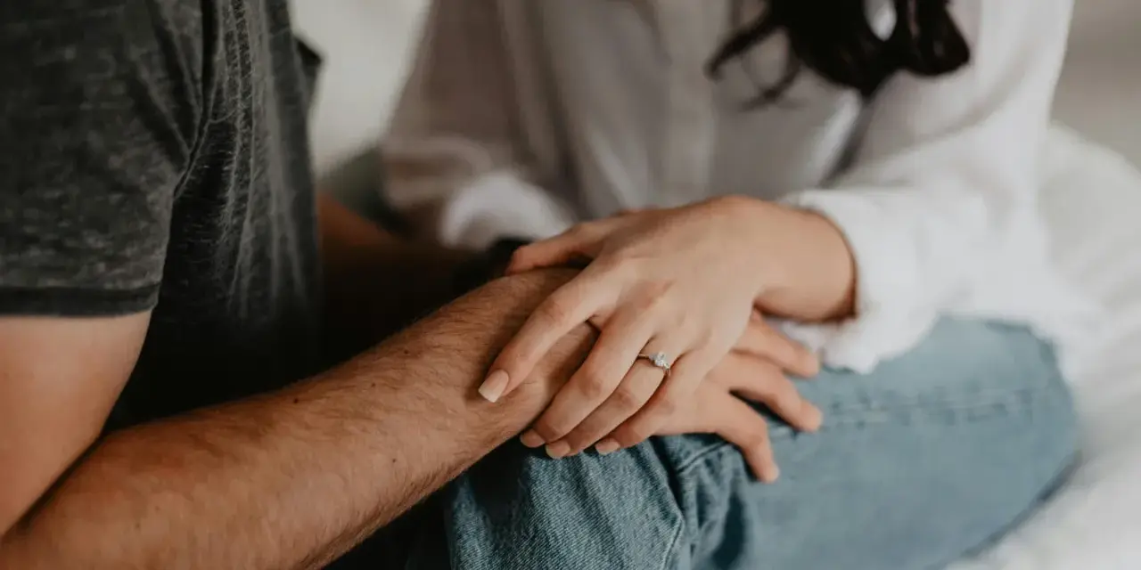 Mains jointes, une bague orne le doigt de la femme, symbole de l'effet boomerang en amour : ce qui est donné revient toujours.