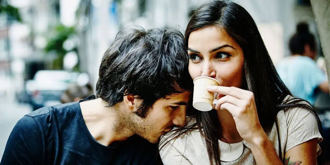 Un homme murmure à l'oreille d'une femme qui boit son café. Un tendre début de relation, peut-être le surnom qu'il vient de lui donner.