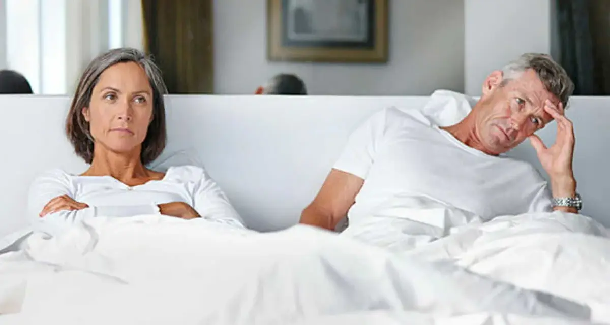 Couple au lit, elle est fâchée, lui semble préoccupé par une perte libido homme 60 ans.