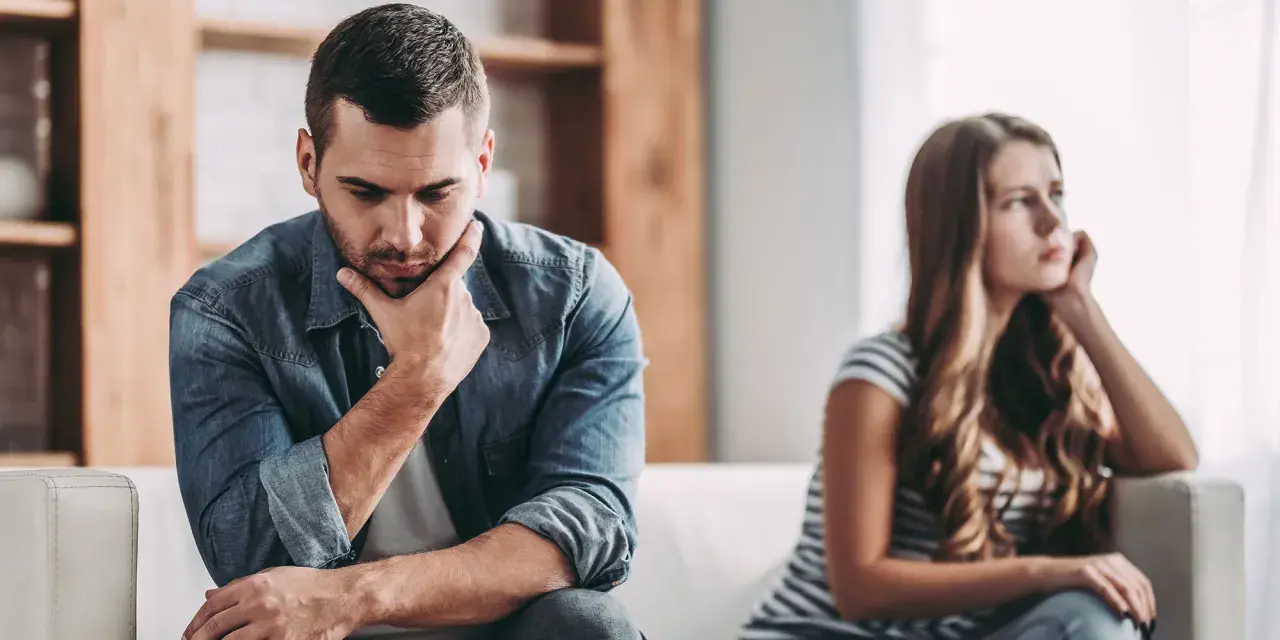 Un homme pensif, peut-être un homme qui trouve toujours des excuses, est assis à côté d'une femme qui regarde au loin, le couple semble distant.