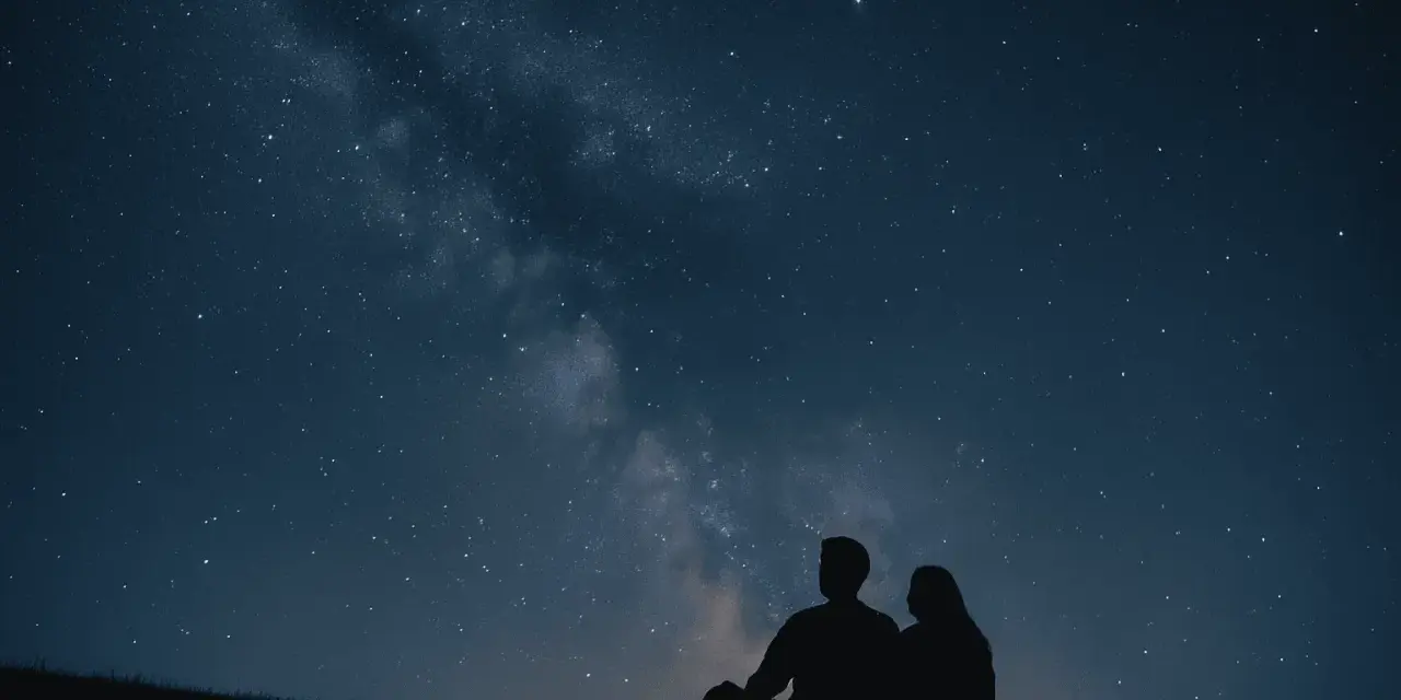 Un couple en silhouette admire la Voie lactée. Une idée de rendez-vous romantique parfait sous les étoiles.