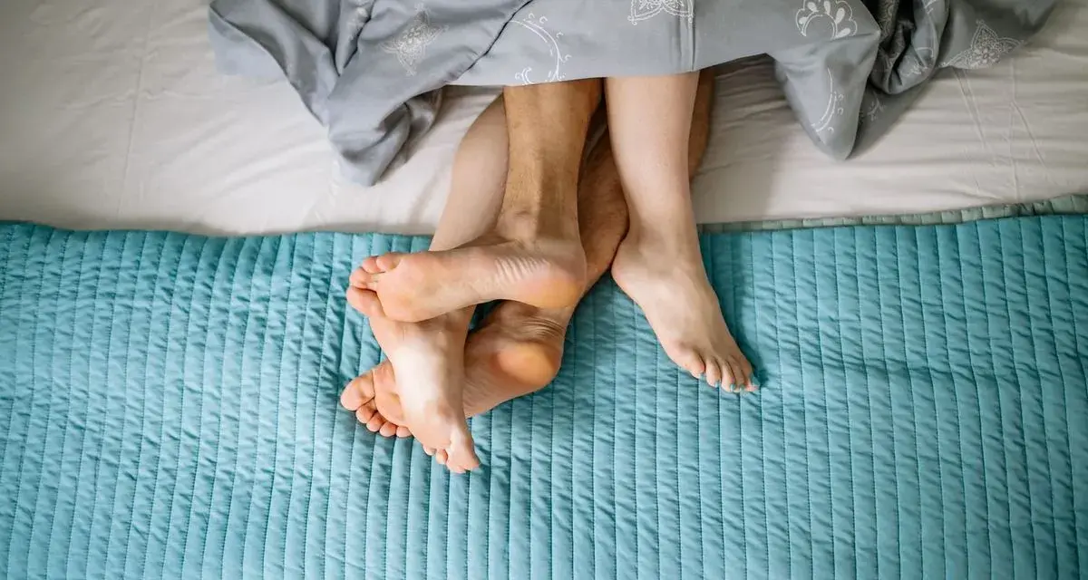 Pieds entrelacés sous une couette, évoquant la chaleur et la libido femme.