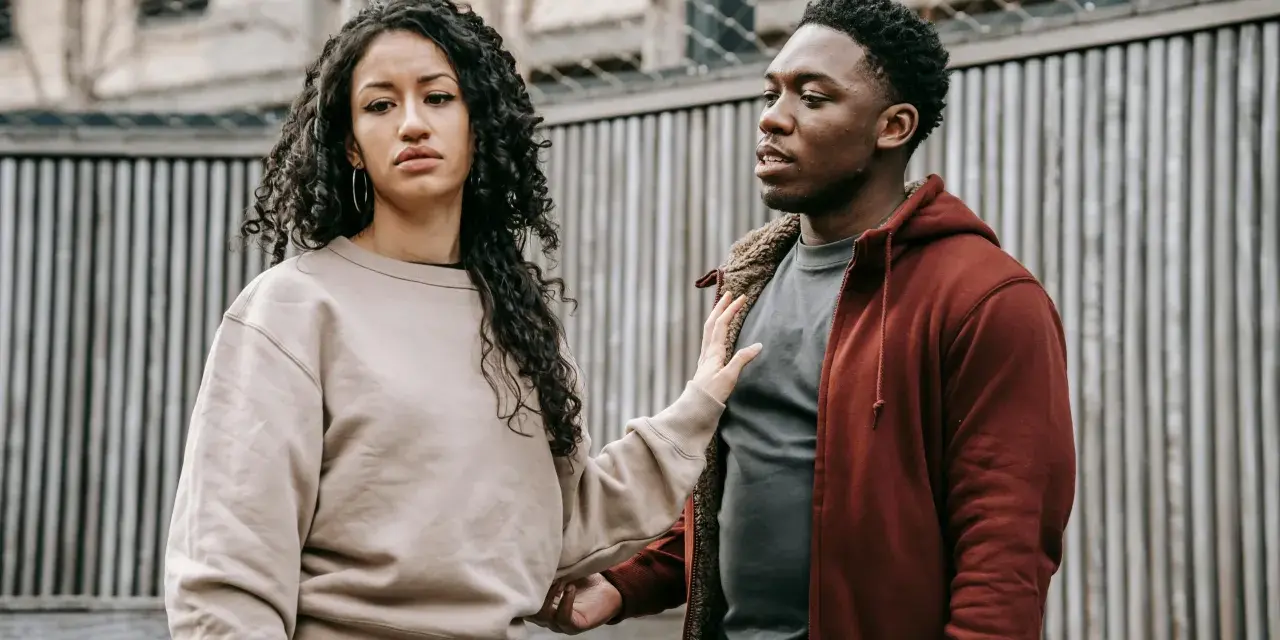 Un homme et une femme se regardent, l'air préoccupé. Sa main sur son bras suggère une tentative de connexion, mais son expression montre qu'il ne veut plus donner de nouvelles, quel effet sur les hommes.