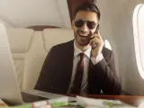 Un homme d'affaires souriant, lunettes de soleil, au téléphone dans un jet privé. Il semble rencontrer un homme riche pour conclure un accord.