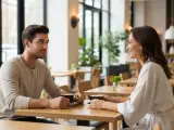 Un couple partage un café, il parle de moi à son entourage, souriant et complice dans un café lumineux.