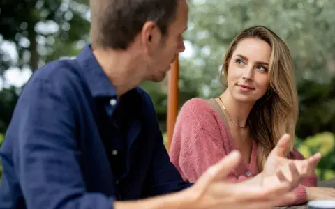 Un homme parle à une femme, son regard captivé par elle. Elle semble écouter attentivement, son expression suggérant le **hero instinct**.