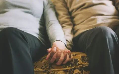 Mains jointes d'un couple qui ne se voit que le week-end, un moment précieux de connexion et de réconfort partagé.