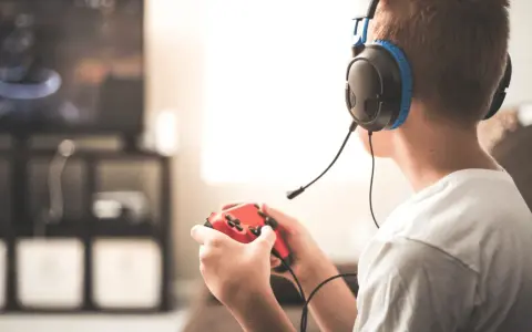 Un jeune homme, casque sur les oreilles, manette rouge en main, plongé dans ses jeux vidéos. Il semble que mon mec préfère ses jeux vidéos à moi.
