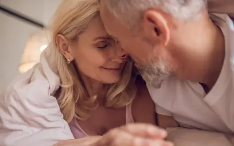 Couple âgé sous une couverture, évoquant la tendresse malgré la baisse de libido chez l'homme de 50 ans.