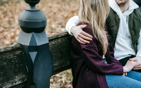 Un homme enlace tendrement une femme assise à ses côtés sur un banc. Un geste qui dit "comment dire je t'aime sans le dire".