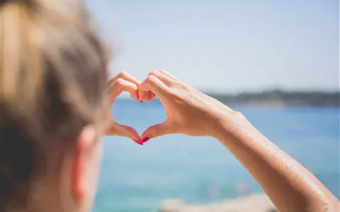Message après premier rendez-vous avec un homme : un cœur formé par des mains mouillées sur fond de mer bleue.