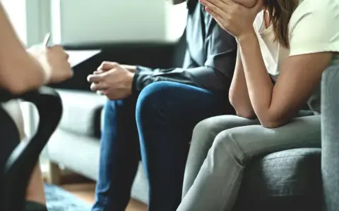 Un couple en pleine thérapie de couples, assis sur un canapé, échangeant avec un thérapeute.