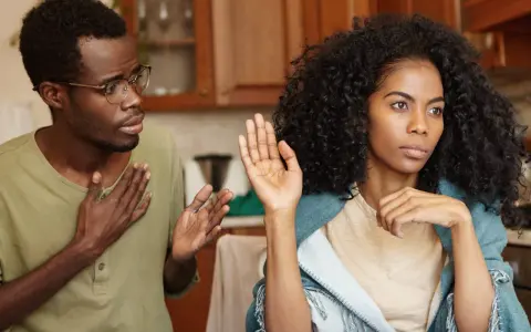 Un homme avec des lunettes parle avec passion, la main sur le cœur, tandis que sa femme, le regard ailleurs, lève une main en signe d'arrêt. Il dit : "je ne supporte plus ma femme.