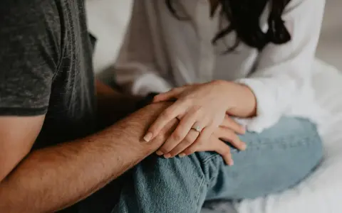Mains jointes, une bague orne le doigt de la femme, symbole de l'effet boomerang en amour : ce qui est donné revient toujours.