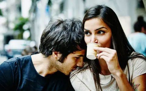 Un homme murmure à l'oreille d'une femme qui boit son café. Un tendre début de relation, peut-être le surnom qu'il vient de lui donner.