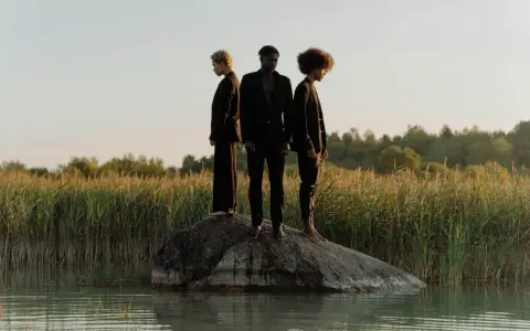 Trois personnes en noir, sur un rocher au milieu de l'eau, symbolisant la non monogamie éthique et la liberté de choix.