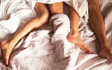 Jambes d'un couple sous la couette, une invitation à explorer comment augmenter sa libido et retrouver l'intimité.