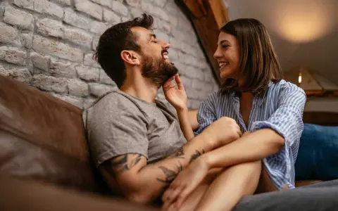 Un couple rit et se regarde tendrement sur un canapé. Le vrai amour, c'est cette complicité.