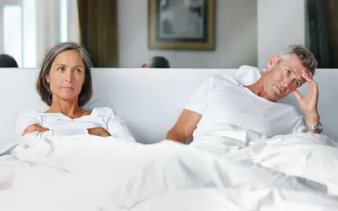 Couple au lit, elle est fâchée, lui semble préoccupé par une perte libido homme 60 ans.