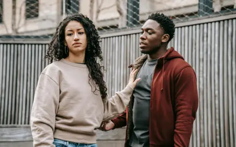Un homme et une femme se regardent, l'air préoccupé. Sa main sur son bras suggère une tentative de connexion, mais son expression montre qu'il ne veut plus donner de nouvelles, quel effet sur les hommes.